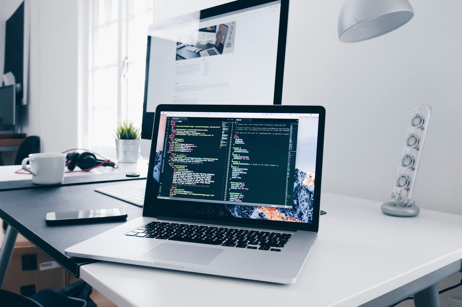 Pengembang bekerja di laptop dengan kode di layar